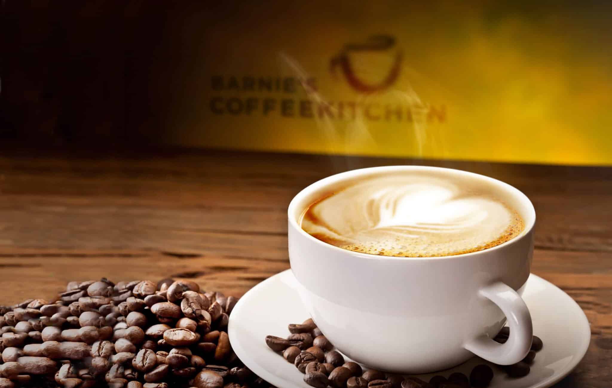 Steaming latte with coffee beans on wooden table.