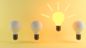 Four light bulbs, one illuminated, yellow background.
