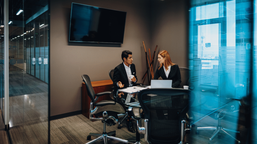 Two professionals discussing in a modern conference room.