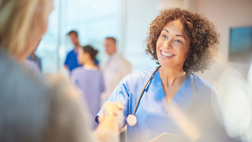 Smiling nurse shaking hands in hospital.