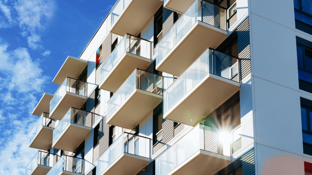 Modern apartment building with glass balconies under sunlight.