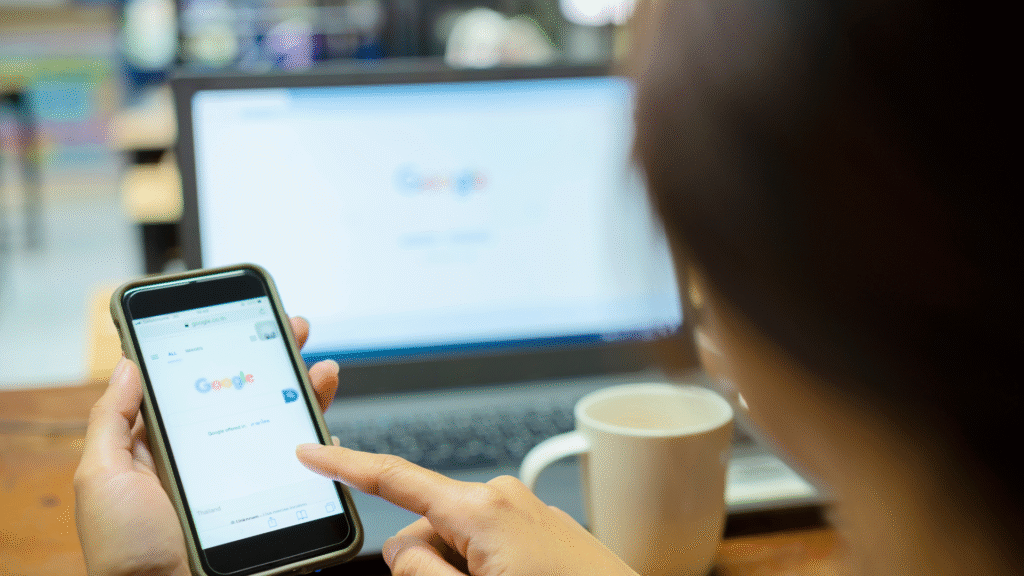 Person using smartphone and laptop with Google search.